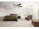 Main bedroom with a ceiling fan, comfortable bed, and relaxing sitting area at 17753 W Columbine Dr, Surprise, AZ 85388