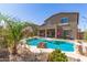 Resort-style pool with built-in bar seating and tropical landscaping in the backyard of the home at 17753 W Columbine Dr, Surprise, AZ 85388