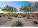 Beautiful backyard with patio furniture nestled beneath the shade of desert trees against a sunset sky at 21934 E Lords Ct, Queen Creek, AZ 85142