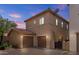 Exterior view showcasing the two-car garage and tile roof against a sunset sky at 21973 N 102Nd Ln # 411, Peoria, AZ 85383