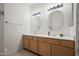 Bright bathroom features double sinks with wood cabinets, two mirrors, and modern lighting fixtures at 2243 E Cortez Dr, Gilbert, AZ 85234