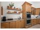 This kitchen features wooden cabinetry, floating shelves with decor, and stainless steel appliances at 2243 E Cortez Dr, Gilbert, AZ 85234