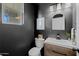 Modern half-bathroom with dark walls, a vanity, unique mirror, and decorative accents at 2661 E Los Alamos Ct, Gilbert, AZ 85295