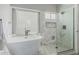 Bright bathroom with a soaking tub next to window and glass enclosed shower featuring stylish herringbone tiling at 3856 E Encinas Ave, Gilbert, AZ 85234