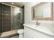 Modern bathroom featuring a glass enclosed shower with dark tile and a stylish vanity with marble countertop at 4628 W Solano S Dr, Glendale, AZ 85301