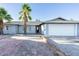 Charming single-story home with gray exterior, a palm tree, and a brick driveway at 4628 W Solano S Dr, Glendale, AZ 85301