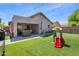 Landscaped backyard with synthetic lawn, play area, patio seating, and string lights at 4704 E Melinda Ln, Phoenix, AZ 85050