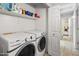 Efficient laundry room with modern washer and dryer, open shelving, and access to a bright bathroom at 4704 E Melinda Ln, Phoenix, AZ 85050