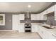 Updated kitchen features stainless steel appliances, a double oven, stylish backsplash, and white cabinets at 5029 W Osborn Rd, Phoenix, AZ 85031