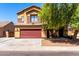 Two-story home featuring a front yard with mature trees and a red two-car garage door at 6320 S 26Th Dr, Phoenix, AZ 85041
