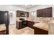 Kitchen with dark cabinetry, stainless steel appliances, and travertine flooring at 6320 S 26Th Dr, Phoenix, AZ 85041