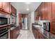 Contemporary kitchen featuring stainless steel appliances, dark wood cabinetry, and tiled flooring at 6838 E Belleview St, Scottsdale, AZ 85257