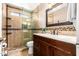 This bathroom has a wood vanity with marble counter, framed mirror, and a tiled walk-in shower at 7749 W Hearn Rd, Peoria, AZ 85381