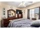 Comfortable bedroom features a plush queen bed, a ceiling fan, and a dark wood dresser with mirror at 7749 W Hearn Rd, Peoria, AZ 85381