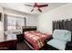 Traditional bedroom features a ceiling fan, dark wood dresser, and a bed with a red quilt at 7749 W Hearn Rd, Peoria, AZ 85381