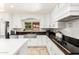 Well-lit kitchen featuring a stainless steel sink, white cabinets, black granite countertops, and mosaic backsplash at 7749 W Hearn Rd, Peoria, AZ 85381
