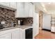 Convenient kitchenette featuring white cabinets, a tiled backsplash, and compact appliances for efficient meal preparation at 7749 W Hearn Rd, Peoria, AZ 85381
