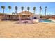 Spacious backyard featuring a pool, covered patio, mature trees, and desert landscaping at 809 N Gilbert Ave, Casa Grande, AZ 85122