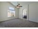 Spacious bedroom with neutral carpet, ceiling fan, and arched entrance to the bathroom at 8370 W Audrey Ln, Peoria, AZ 85382