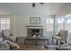 Living room with a stone fireplace, large windows, neutral seating, and a ceiling fan at 8370 W Audrey Ln, Peoria, AZ 85382
