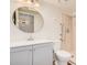 Well-lit bathroom featuring a round mirror, single sink vanity, and a walk-in shower with grab bars at 927 E Charleston Ave, Phoenix, AZ 85022