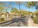 View of the community gate with desert landscaping, mature trees, and well-paved roads at 9661 E Glencove Cir, Mesa, AZ 85207