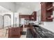 Modern kitchen with dark wood cabinets, black countertops, and stainless steel appliances at 9661 E Glencove Cir, Mesa, AZ 85207