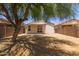 A gravel backyard features a covered patio, with a privacy wall and mature tree at 9717 W Purdue Ave, Peoria, AZ 85345