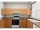 Kitchen featuring an electric range, wood cabinets, and neutral countertops at 9717 W Purdue Ave, Peoria, AZ 85345