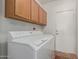 The laundry room features a white washer and dryer, with wooden cabinets above at 9717 W Purdue Ave, Peoria, AZ 85345