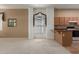 Open-concept living area flows into the kitchen, featuring neutral carpet, large windows, and bar seating at 9717 W Purdue Ave, Peoria, AZ 85345