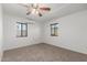 A simple bedroom with neutral carpet, a ceiling fan, and two windows at 9801 N 56Th Dr, Glendale, AZ 85302
