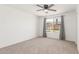 A simple bedroom with neutral carpet, a ceiling fan, and a large window at 9801 N 56Th Dr, Glendale, AZ 85302