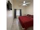 Bedroom with ceiling fan, TV, and a queen-sized bed with a red comforter at 1038 S Palomino Creek Dr, Gilbert, AZ 85296