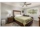 Bedroom with a tufted headboard bed, ceiling fan, wood-look tile, and a writing desk at 10702 W Salem Dr, Sun City, AZ 85351