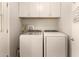 Well-lit laundry room with modern, white washer and dryer and ample storage space above at 10702 W Salem Dr, Sun City, AZ 85351