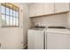 Bright laundry room with window and overhead cabinets; newer washer and dryer are featured at 10702 W Salem Dr, Sun City, AZ 85351