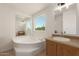 Bright bathroom featuring a soaking tub, vanity with mirror, and a window with an outdoor view at 13217 S Tuthill Rd, Buckeye, AZ 85326