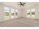 Bright living area offering neutral carpet, ceiling fan, and multiple windows letting in natural light at 13217 S Tuthill Rd, Buckeye, AZ 85326