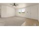 A bright living room with neutral carpet, ceiling fan, and ample natural light coming through a window at 13217 S Tuthill Rd, Buckeye, AZ 85326