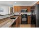 Well-lit kitchen with wood cabinets, granite countertops, and black appliances at 1350 S Greenfield Rd # 2133, Mesa, AZ 85206