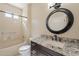 Well-lit bathroom featuring granite countertop vanity, round mirror, and a shower-tub combination at 15936 W Kino Dr, Surprise, AZ 85374