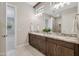 Bathroom featuring double sink vanity, granite countertops, and a tiled walk-in shower at 17183 W San Marcos St, Surprise, AZ 85388