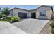 Charming single-story home featuring desert landscaping, a dark garage door, and a spacious paved driveway at 17183 W San Marcos St, Surprise, AZ 85388
