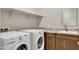Functional laundry room featuring a granite countertop, sink, and modern washer and dryer at 17183 W San Marcos St, Surprise, AZ 85388