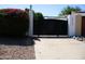 Home's driveway gate entrance is secured by a black metal gate surrounded by lush bougainvillea and rock landscaping at 2068 E Cairo Dr, Tempe, AZ 85282