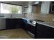 Well-lit kitchen with black cabinets, tile backsplash, stainless steel appliances, and white countertop at 2068 E Cairo Dr, Tempe, AZ 85282