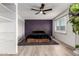 Bedroom with a striking purple accent wall, ceiling fan, plush bedding, and light wood floors at 2423 E Dahlia Dr, Phoenix, AZ 85032