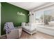 Cozy Bedroom with an accent green wall, a crib, rocking chair and bright window at 2423 E Dahlia Dr, Phoenix, AZ 85032