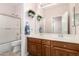 Bathroom with dual sinks, wooden cabinets, and shower-tub combo at 25633 N 71St Dr, Peoria, AZ 85383